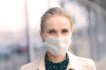 Confident woman wearing face mask and talking with somebody on mobile during coronavirus pandemic.