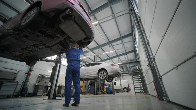 Car mechanic replacing car wheel brake shoes of lifted automobile at repair service station