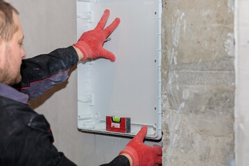 The electrician tries on and marks the lines of the electrical panel.