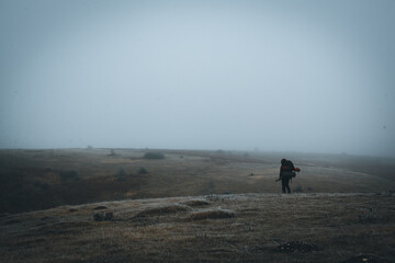 A backpacker traveler trying to find his way through the fog.