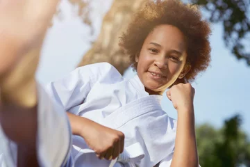 Tuinposter Cheerful Afro American girl practicing martial arts outdoors © Kostiantyn