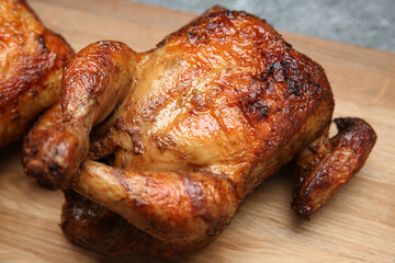 Delicious grilled whole chicken on wooden board, closeup
