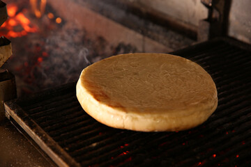 Baking pita bread on grilling grate in oven, closeup