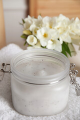 Fototapeta na wymiar Jar of natural exfoliating salt scrub on white towel