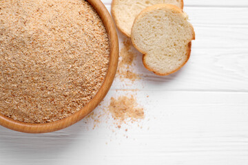 Fresh breadcrumbs on white wooden table, flat lay