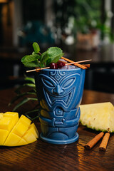 Refreshing cold Tiki Drink Cocktail with pineapple, mango, mint and cinnamon 