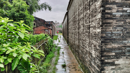 Narrow street between old concrete houses in the village. Rainy weather. Kaiping diaolou and villages. China. Asia