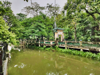 Fototapeta na wymiar Small river in the park. A gazebo in the Chinese style. Tropical vegetation and wet weather. Kaiping diaolou and villages. UNESCO World Heritage Site. China. Asia