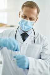 Male doctor in sterile gloves holding test tube