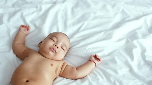 Close up portrait of adorable funny african american baby sleeping deeply on white bedclothes, empty space