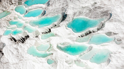 Aerial of the famous Pamukkale travertines in central western turkey. Famous for their turquoise thermal pools and pure white carbon deposits closeup overhead