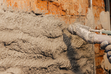 Obraz premium Semi-automatic wall plastering process. The plaster solution is thrown out of the sprayer onto the wall.