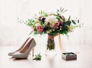 Fototapeta premium Bridal bouquet and white shoes on the table. Wedding accessories of the bride