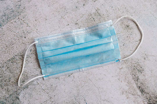 Used surgical face mask isolated on concrete floor