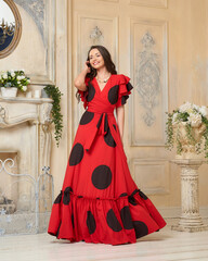 Elegant caucasian woman with long brunette hair wearing red and black polka dot wrap dress with belt