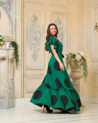 Pretty caucasian girl wearing green polka dot wraped dress with belt, standing and posing in bright...