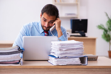 Naklejka premium Young male employee unhappy with excessive work in the office
