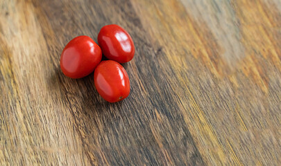 red cherry three tomatoes on a wooden background close-up vegetable set