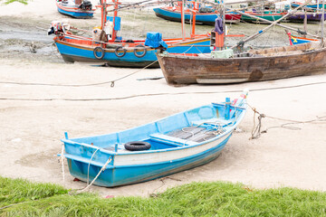 blue boat on the sandy shore in the background of fishing boats