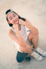 Asian Beautiful women surf skate or skateboard outdoors on beautiful summer day. Happy young women play surf skate at park near the beach on morning time. Sport activity lifestyle concept.