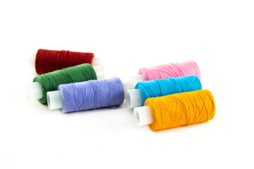 assorted threads on a white bobbin multi-colored thread dark red, blue and yellow on an isolated background