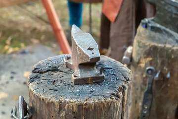 iron anvil traditional on a wooden deck on a blurred forge background