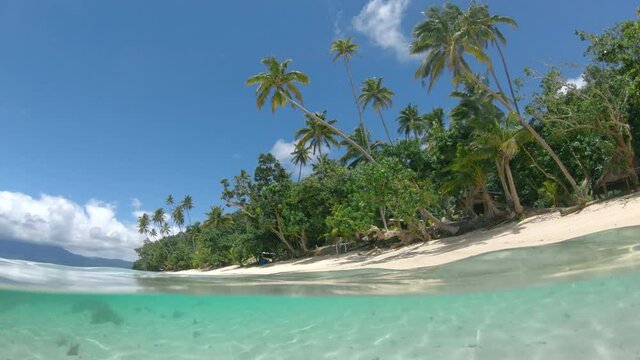 HALF HALF: Mesmerizing view of the sky above sandy shoreline from the clear blue water surrounding it. Exploring underwater world on Fiji island. Glass like sea surface glistening on the ocean floor