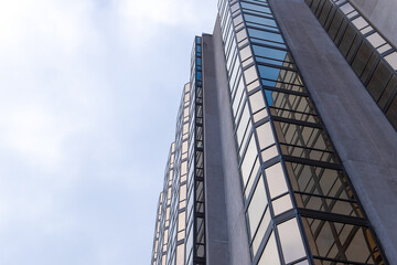 The exterior wall of a contemporary commercial style building with aluminum metal composite panels and glass windows. The futuristic building has engineered diagonal cladding steel frame panels. 