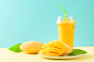 Fresh mango smoothie in a glass and sliced ripe mango fruit on color background, Tropical drink