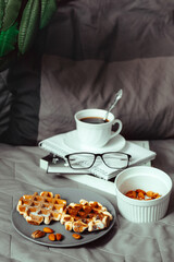 Viennese waffles and coffee in bed. Morning breakfast. Waffles with almond flour. A healthy snack. Still life on a gray bed