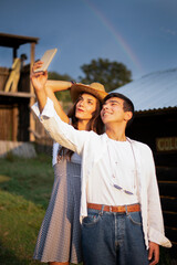 Two Friends Smiling and Taking selfie Pictures with a Rainbow in the Ranch.
