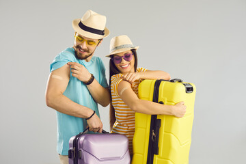 Happy family ready for safe summer vacation. Smiling young couple holding travel cases and showing...