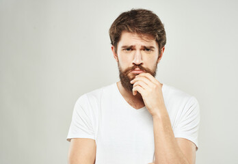 a man with a puzzled look looks to the side on a light background and a thick beard