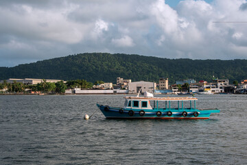Fototapeta na wymiar Small colorful fishing boat stopped in the port channel of the city of Santos. In the background, Santa Cruz dos Navegantes, a fishing village in the city of Guarujá.