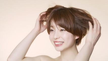 Fototapeta premium 髪をくしゃくしゃにするショートヘアの女性 ヘアケアイメージ 