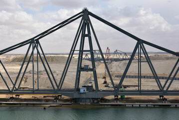 Landscape of Suez Canal, view from transiting cargo ship. Bridge construction on the Canal bank. 