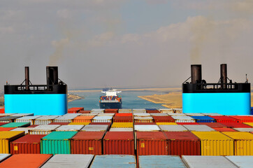 Container ship transiting through Suez Canal. View on the funnels standing above loaded containers. 