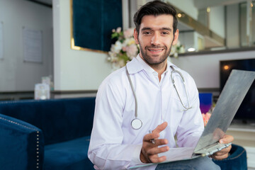 Confident doctor wearing lab coat and stethoscope sitting on sofa at the modern beauty clinic....