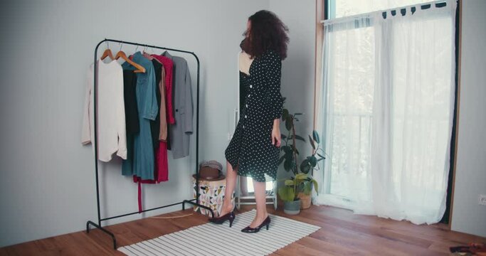 Trying New Clothes On. Happy Young Female Fashion Blogger With Curly Hair Posing At Mirror In New Dress And Trendy Shoes