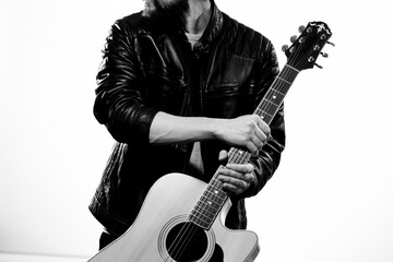 A man with a guitar black leather jacket light background performing a musician