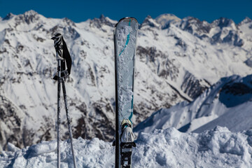 Skiing and ski poles stand vertically in the snow against the background of the ski descent