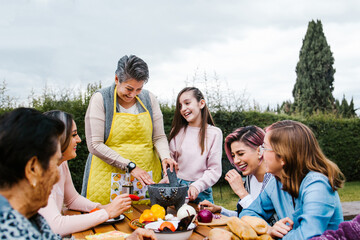 three generations of mexican women grandmother and daughter cooking spicy sauce at home in Mexico city