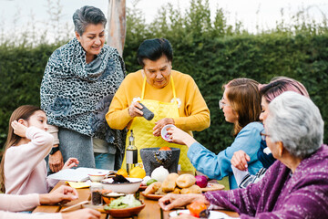 latin grandmother and granddaughter, daughter cooking mexican food at home, three generations of...