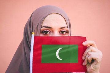 Muslim woman in hijab holds flag of Maldives