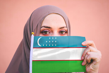 Muslim woman in hijab holds flag of Uzbekistan