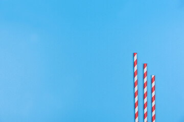 Three tubes for cocktails lie on a blue background.