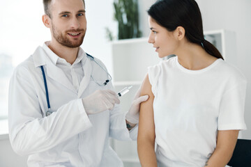 Obraz premium professional doctor injects a vaccine on a female patient's shoulder