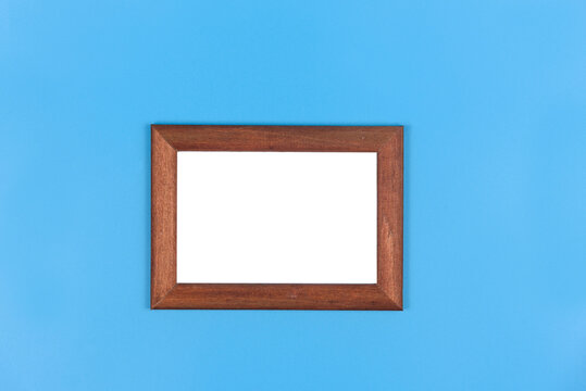 Brown wooden frame for a photo on a blue background.