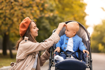 Woman and her cute baby in stroller outdoors