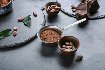 Cacao powder with beans and chocolate on dark background